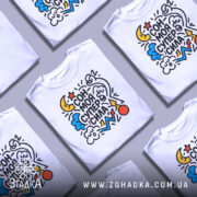 Футболка сон моя суперсила. Біла футболка на манекені, з яскравим принтом, що містить зірки, хмари, місяць та інші елементи. Фон нейтральний, що підкреслює кольори принта.