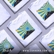 Футболка сонце в Україні, біла, зображена на манекені, фон світло-сірий, принт з жовтими та блакитними променями, чорні гори та синє сонце.