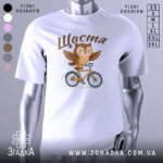 Футболка сова щастя, біла, зображена на манекені, фон градієнтний сірий, принт з совою на велосипеді, з розкритими крилами, текст 'Щастя' зверху.