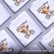 Футболка сова щастя, біла, зображена на манекені, фон градієнтний сірий, принт з совою на велосипеді, з розкритими крилами, текст 'Щастя' зверху.