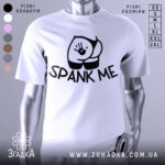 Футболка спанк-арт білого кольору, зображена на манекені з правого боку, фон світло-сірий, принт з чорним малюнком у вигляді сідниць з відбитком руки та написом 'SPANK ME'.