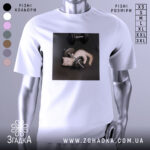 Футболка спорт котик, біла, зображена на манекені, фон світло-сірий, принт з котиком, що грає з гантелями на чорному фоні.