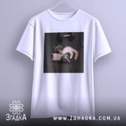 Футболка спорт котик, біла, підвішена на вішалці, фон світло-сірий, принт з котиком, що грає з гантелями на чорному фоні.