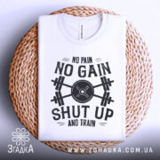 Футболка спортивний дух, біла, складена на плетеній кошику, фон білий, принт чорного кольору з написом 'NO PAIN NO GAIN SHUT UP AND TRAIN' та зображенням гантель.
