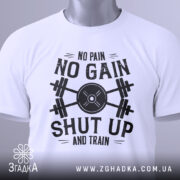 Футболка спортивний дух, біла, складена на поверхні, фон світло-сірий, принт чорного кольору з написом 'NO PAIN NO GAIN SHUT UP AND TRAIN' та етикетка з зеленим шнурком.