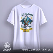 Футболка справжній чоловік, біла, зображена з фронтального ракурсу, на фоні світло-сірого кольору, принт з двома сокирами та горами, текст українською мовою.