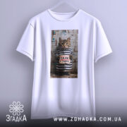 Футболка срав в тапок, біла, зображення кота в смугастій формі, підвішена на вішалці, принт з написом 'SRAV v TAPOK'.