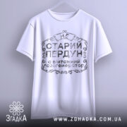 Футболка старий пердун, біла, підвішена на вішалці, фон світлий, принт чорного кольору з декоративними елементами.