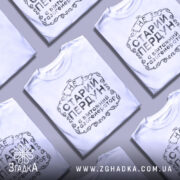 Футболка старий пердун, біла, зображена на манекені, фон нейтральний, принт чорного кольору з декоративними елементами.