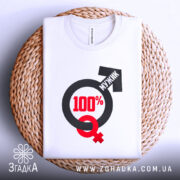 Футболка сто відсотків мужик, біла, зображена на плоскій поверхні, фон світло-сірий, принт містить символи чоловічої та жіночої статі, текст "100%" червоного кольору, а слово "МУЖИК" чорного кольору, футболка розташована на плетеній основі.