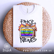 Футболка стоп фейкам, складена біла футболка на плетеній основі, з принтом телевізора, кольоровими смужками та написом 'FAKE NEWS', фон світлий.