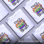 Футболка стоп фейкам, біла футболка на манекені, з принтом телевізора з веселим обличчям та кольоровими смужками, напис 'FAKE NEWS' з вогнем навколо, фон світлий.