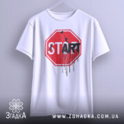 Футболка стоп старт арт, біла, підвішена на вішалці, фон світло-сірий, принт червоного кольору у формі знака стоп з написом 'START' чорним кольором, з елементами графіті.
