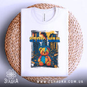 Футболка стоп війна, біла, складена на плетеній кошику, фон світлий, принт з ведмедиком, яскраві кольори, видно етикетку.