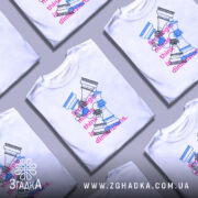 Футболка стратегічні шахи білого кольору, зображена на манекені, фон світло-сірий, принт з шаховими фігурами в блакитному та рожевому кольорах, текст на футболці читається: 'strategic minds think in dimensions.'