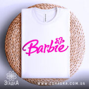 Футболка стиль барбі, біла, складена на плетеній основі, фон світлий, принт з написом 'Barbie' яскравого рожевого кольору.