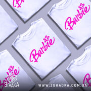 Футболка стиль барбі, біла, зображена на манекені, фон нейтральний, принт з написом 'Barbie' яскравого рожевого кольору з квіткою.