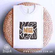 Футболка стиль NICE, біла, складена на плетеній кошику, фон світло-сірий, принт з геометричним малюнком та написом 'NICE' оранжевого кольору.