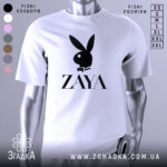 Футболка стиль зая білого кольору, зображена з фронтального ракурсу на манекені, фон світло-сірий, принт чорного кольору з логотипом ZAYA та зображенням зайця в смокінгу.
