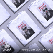 Футболка стильна бабуся, біла, з прямим ракурсом, на фоні світло-сірого кольору, принт з зображенням бабусі в чорних окулярах, з червоними губами, в шкірянці, з написом 'Normal is boring' червоним шрифтом.