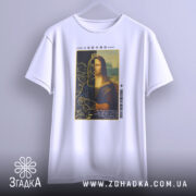Футболка сучасна моналіза, білого кольору, підвішена на вішалці, фон світло-сірий, принт з Моною Лізою з короною, текст на принті видно, деталі графіки включають рослинні елементи.