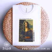 Футболка сучасна моналіза, білого кольору, зображена в плоскому вигляді на плетеній основі, фон світлий, принт з Моною Лізою з короною, текст на принті чітко видно, деталі графіки включають рослинні елементи.