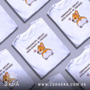 Футболка сумненькою дупцею не пукнеш. Біла футболка з принтом корги, що повертається, на фоні світло-сірого градієнту. Принт зображує корги з сердечком, що виглядає весело, з акцентом на його дупцю.