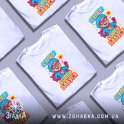 Футболка супер бабуся, білого кольору, зображена на манекені з правого боку, фон світло-сірий, принт з веселим персонажем у червоному плащі та окулярах, текст 'СУПЕР БАБУСЯ' яскравими кольорами.