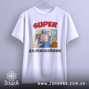 Футболка супер далекобійник білого кольору, зображена з фронтального ракурсу, фон нейтральний, принт з мультяшним водієм у синій кепці, текст 'SUPER ДАЛЕКОБІЙНИК' червоного кольору, футболка підвішена на вішалці.