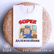 Футболка супер далекобійник білого кольору, зображена зверху на плетеній основі, фон світлий, принт з мультяшним водієм у синій кепці, текст 'SUPER ДАЛЕКОБІЙНИК' червоного кольору, видно комір футболки.