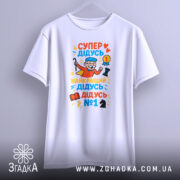 Футболка супер дідусь герой, біла, зображена з фронтального ракурсу, на фоні світло-сірого кольору, принт яскравий, з малюнком дідуся в червоному плащі, який тримає шахову фігуру та медаль.