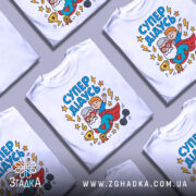 Футболка супер дідусь білого кольору, зображена з фронтального ракурсу на манекені, фон світло-сірий, принт з веселим дідусем у червоному плащі та хлопчиком, що тримається за його плечі, оточений зірками та блискавками.