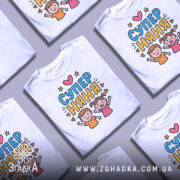 Футболка супер няня, біла, зображена на манекені, фон світло-сірий, принт з двома дітьми, які радісно піднімають руки, текст 'СУПЕР НЯНЯ' у яскравих кольорах.