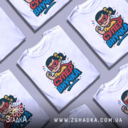 Футболка супер внучка білого кольору, зображена на манекені, з принтом, що зображує дівчинку-супергероя з червоними окулярами та жовтою футболкою, фон світлий, принт яскравий і кольоровий.