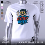 Футболка супер внук білого кольору, зображена на манекені, ракурс спереду, фон світло-сірий, принт з веселим персонажем у масці та плащі, з піднятою рукою, текст 'СУПЕР ВНУК' яскравими кольорами.