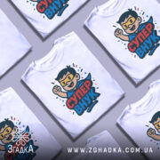 Футболка супер внук білого кольору, зображена на манекені, ракурс спереду, фон світло-сірий, принт з веселим персонажем у масці та плащі, з піднятою рукою, текст 'СУПЕР ВНУК' яскравими кольорами.