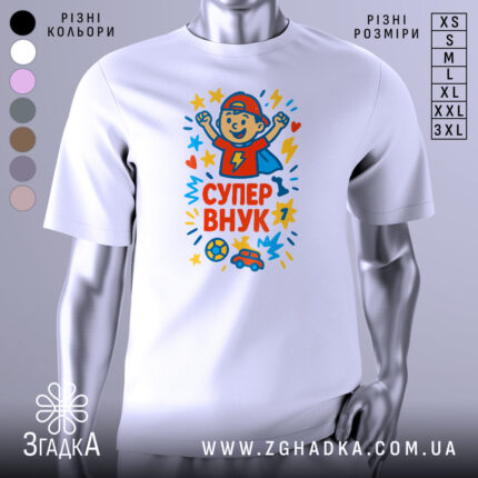 Футболка супер внук білого кольору, зображена на манекені, з принтом, що містить малюнок хлопчика в червоній кепці, який піднімає руки вгору, оточений зірочками та сердечками, на фоні світло-сірого кольору.