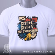 Футболка суперсили копіювання, біла, зображена зверху, складена на поверхні, фон світло-сірий, принт з текстом "Ctrl + C Ctrl + V мої суперсили" яскравих кольорів, з етикеткою на комірці.