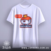 Футболка суші король, біла, підвішена на вішалці, фон світлий, принт з веселим суші персонажем у червоному капелюшку та написом 'Піддані, несіть більше соєвого соусу!', видно деталі швів.