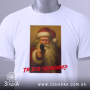 Футболка суворий Санта, біла, зображена зверху, фон світлий, принт з зображенням Санти з пістолетом, текст червоним шрифтом "ТИ БУВ ЧЕМИМ?", на футболці є етикетка.