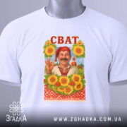 Футболка сват білого кольору, складена на поверхні, фон світло-сірий, принт з усміхненим чоловіком у традиційному вбранні на фоні соняшників, напис 'СВАТ' червоним кольором вгорі, на футболці є етикетка з зеленим шнурком.