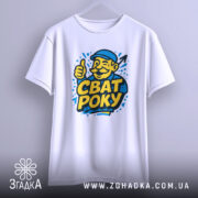 Футболка сват року, біла, підвішена на вішалці, фон світло-сірий, принт з усміхненим чоловіком у капелюсі, який піднімає великий палець, текст "СВАТ РОКУ" яскраво-жовтого кольору.