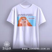Футболка світла вже не треба. Біла футболка з коротким рукавом, підвішена на вішалці, з видимим принтом. Фон світло-сірий. Принт з ілюстрацією дівчини з рудим волоссям, яка дивиться вгору, з текстом на українській мові.