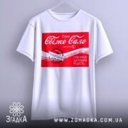 Футболка свіже сало білого кольору, підвішена на вішалці, з принтом червоного кольору, що містить текст "Свіже сало" та інші деталі, фон світло-сірий.