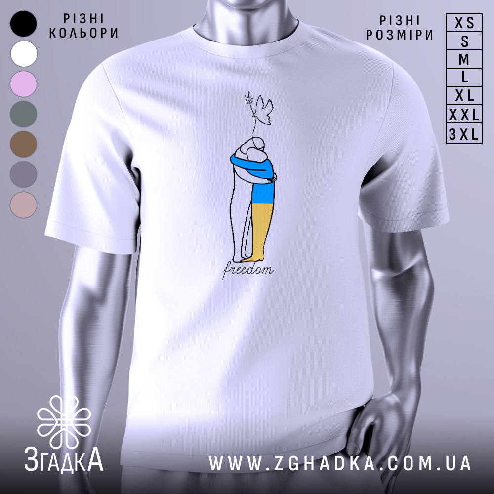 Футболка свобода Україна, біла, зображена на манекені з ближнього ракурсу, фон нейтральний, принт з двома фігурами, одна з яких тримає жовту і синю смугу, напис 'freedom' під малюнком.