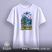 Футболка сила дронів, біла, зображена на вішалці, фон світло-сірий, принт з військовим, що керує дронами, з написом 'СИЛА ДРОНІВ' у жовтому кольорі.