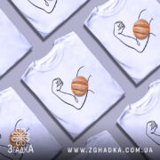 Футболка сила хліба, біла футболка на манекені, зображення руки з м'ячем хліба на передній частині, фон світло-сірий, принт виконаний у чорному кольорі.