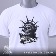 Футболка сила меседжу: біла футболка, складена на поверхні, принт з черепом та короною свободи, ракурс зверху, фон світло-сірий, на футболці є етикетка з зеленим шнурком.