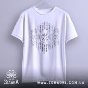 Футболка сила предків. Біла футболка, підвішена на вішалці, з фронтального ракурсу. Принт з символами в чорному кольорі займає центральну частину. Фон світло-сірий, що підкреслює яскравість футболки.