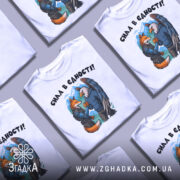 Футболка сила в єдності, біла, зображена на манекені, фон світло-сірий, принт з двома персонажами: лисицею та орлом, які стискають руки, на лисиці броня, на орлі светр, на задньому плані гори.